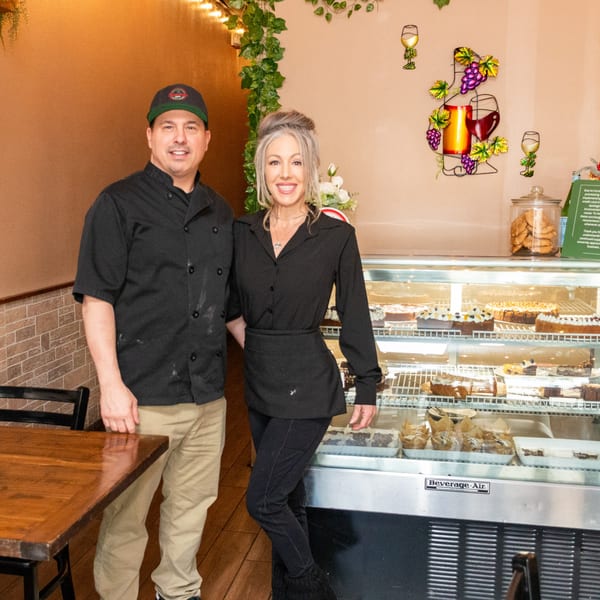 Tarantino's Vegan owners, a man and woman, smiling in front of a dessert display case.