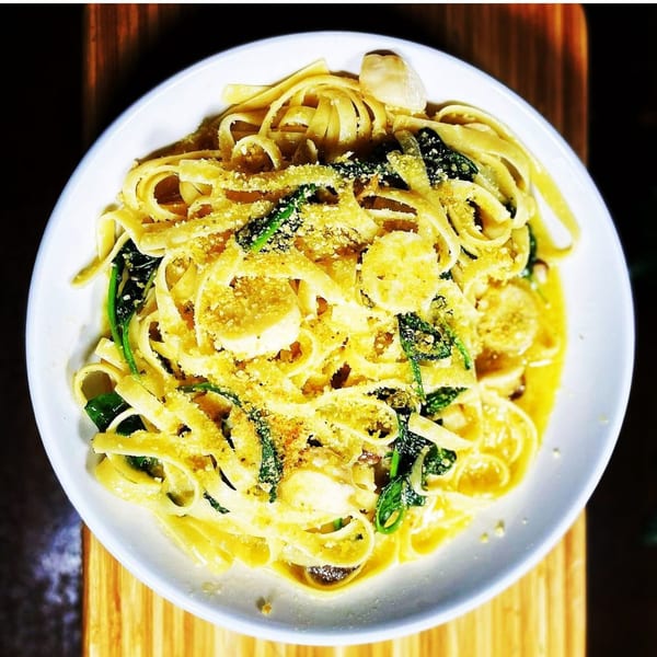 Vegan fettuccine alfredo with spinach, vegan scallops, and grated vegan parmesan cheese.